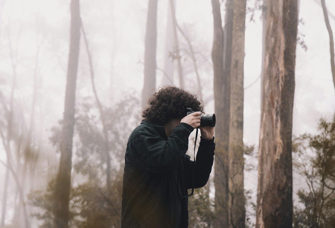 Fotograf fotografiert mit Kamera im nebligen Wald